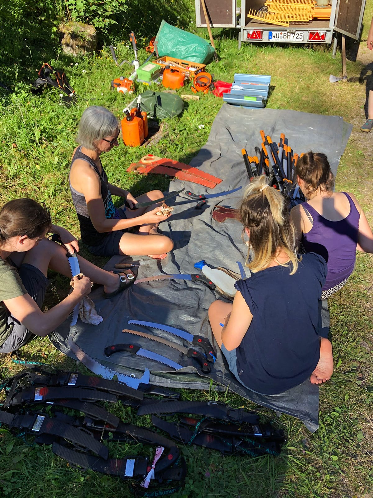 Gruppe bei der Werkzeugpflege im Wald im Sommer