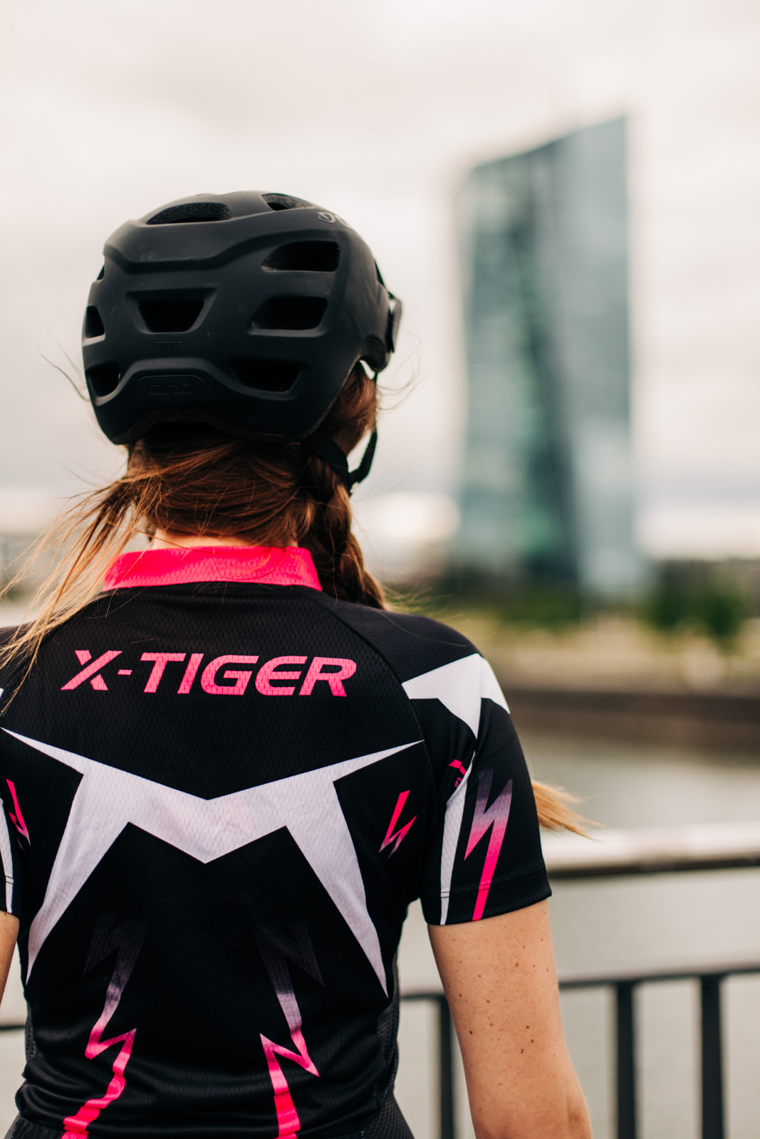Frau mit x-tiger Fahrradbekleidung von hinten schaut auf Skyline