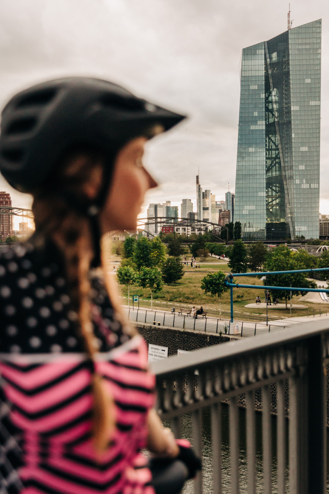 Frau mit Fahrradhelm auf Brücke vor der Europäsischen Zentralbank