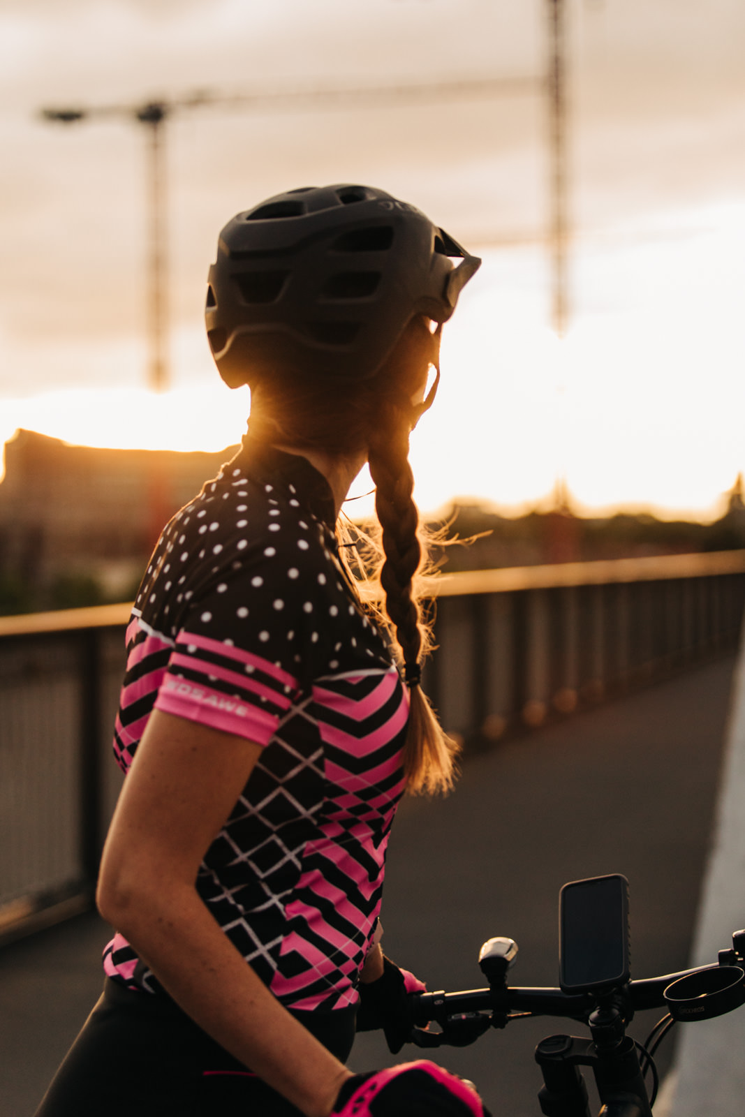 Frau mit Fahrradhelm und Fahrradkleidung beim Sonnenuntergang