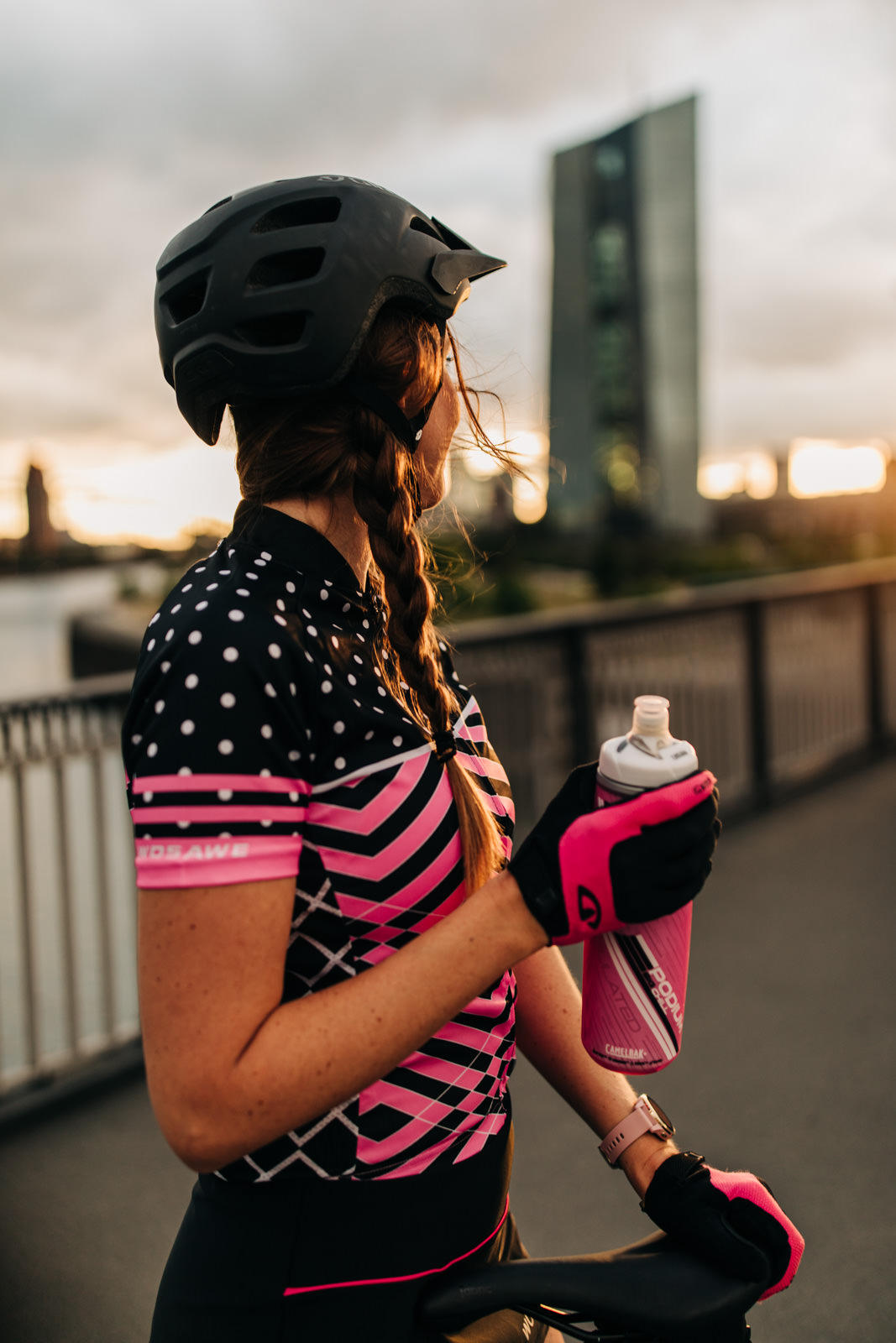 Frau auf Brücke mit Fahrradflasche beim Sonnenuntergang