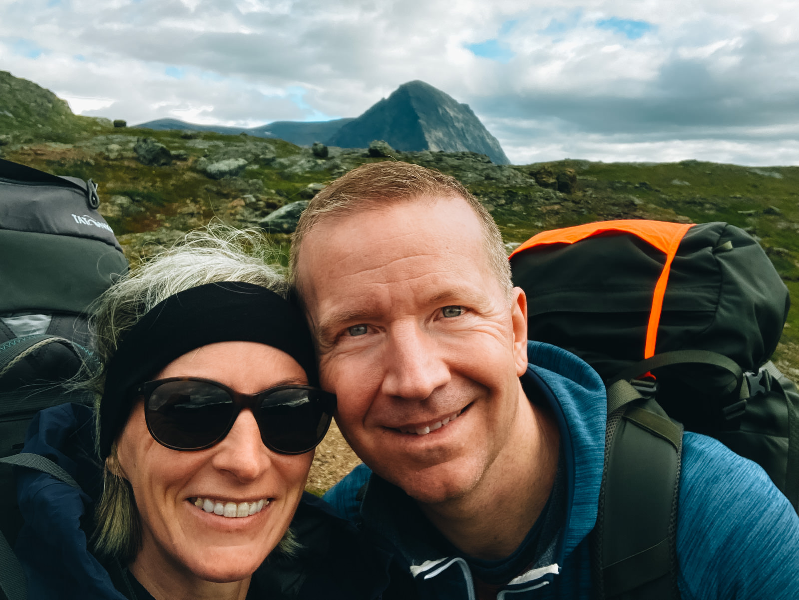 Paar lacht in die Kamera mit einem schwedischen Berg im Hintergrund