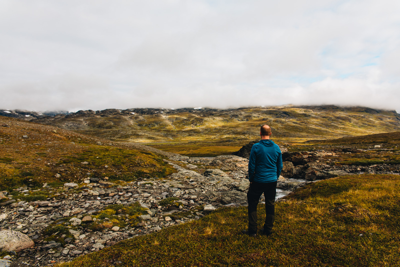 Mann steht im schwedischen Fjell vor großartiger Landschaft