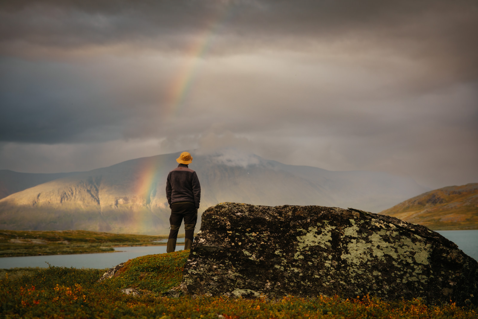 Ein Mann steht in Schweden vor einem Regenbogen beim Fjällräven Classic