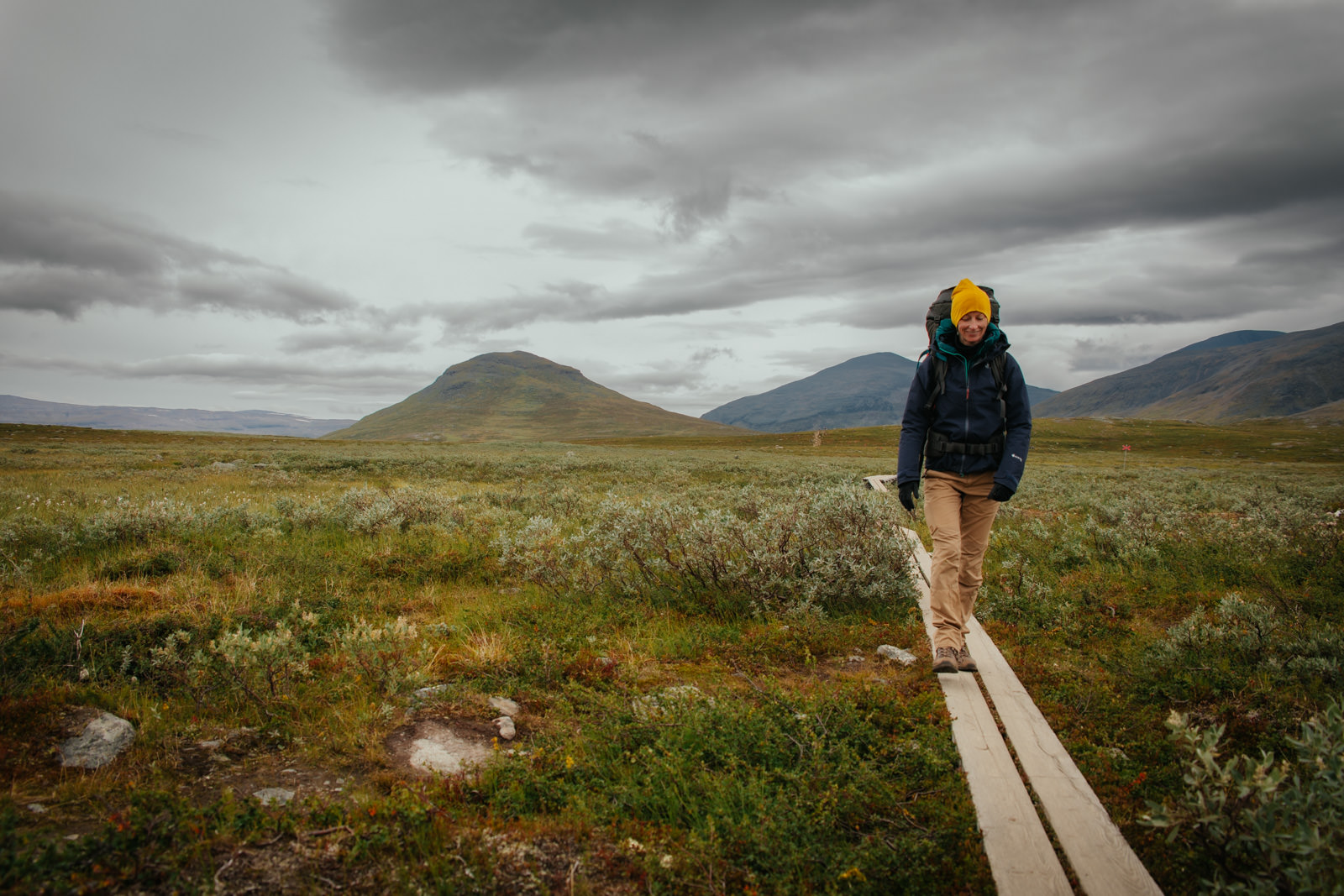 Frau wandert auf Holzbalken durch die Landschaft auf dem Kungsleden in Schweden